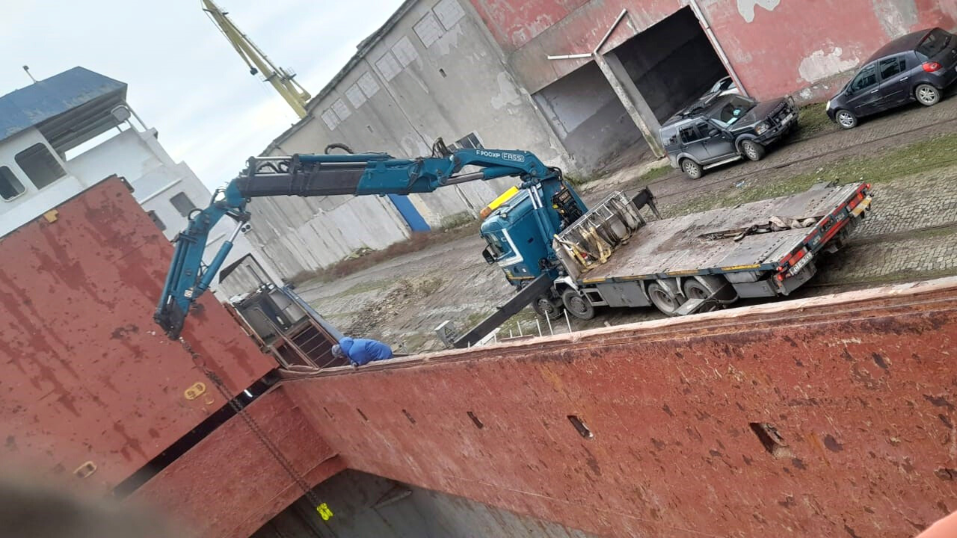 Încărcare de materiale grele într-o navă de marfă folosind un camion macara